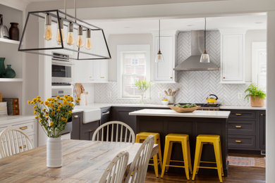 Farmhouse medium tone wood floor kitchen photo in DC Metro with a farmhouse sink, shaker cabinets, black cabinets, quartz countertops, white backsplash, an island and white countertops
