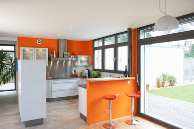 Offene, Geräumige Moderne Küche in U-Form mit flächenbündigen Schrankfronten, Halbinsel, grauen Schränken, Granit-Arbeitsplatte, Keramikboden und grauem Boden in Nürnberg