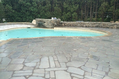 Modelo de piscina con fuente tradicional renovada de tamaño medio tipo riñón en patio trasero con adoquines de piedra natural