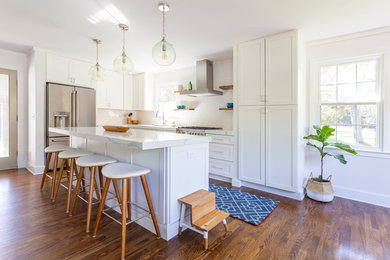 Eat-in kitchen - mid-sized contemporary u-shaped medium tone wood floor and brown floor eat-in kitchen idea in Charleston with an undermount sink, shaker cabinets, white cabinets, granite countertops, white backsplash, subway tile backsplash, stainless steel appliances, an island and white countertops