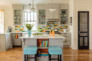 Inspiration for a mid-sized cottage l-shaped medium tone wood floor and brown floor eat-in kitchen remodel in Little Rock with a farmhouse sink, shaker cabinets, gray cabinets, multicolored backsplash, stainless steel appliances, an island, quartz countertops, ceramic backsplash and white countertops