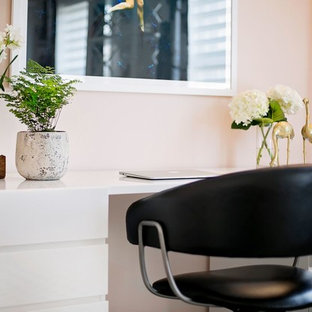 This is an example of a medium sized modern home office and library in New York with pink walls, carpet, a freestanding desk and no fireplace.