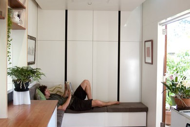 Diseño de salón abierto actual pequeño sin chimenea y televisor con paredes blancas y suelo de madera oscura
