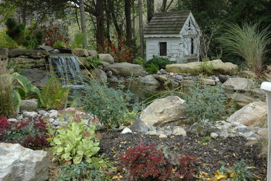 This is an example of a country backyard shaded garden for spring in New York with natural stone pavers.