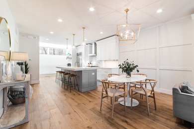 Inspiration for a large transitional open plan dining in Chicago with white walls, medium hardwood floors, a standard fireplace, a concrete fireplace surround and brown floor.