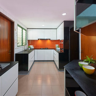 Idéer för mellanstora funkis kök, med en enkel diskho, släta luckor, vita skåp, granitbänkskiva, orange stänkskydd, glaspanel som stänkskydd, rostfria vitvaror och klinkergolv i keramik