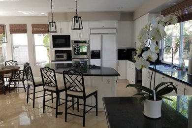 Inspiration for a mid-sized timeless u-shaped beige floor eat-in kitchen remodel in San Diego with an undermount sink, recessed-panel cabinets, white cabinets, quartz countertops, paneled appliances, an island and black countertops