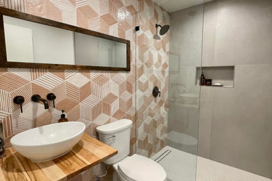 Bathroom - mid-sized eclectic gray tile and ceramic tile ceramic tile, gray floor and single-sink bathroom idea in Los Angeles with a one-piece toilet, orange walls, a vessel sink, wood countertops, brown countertops, a niche and a floating vanity