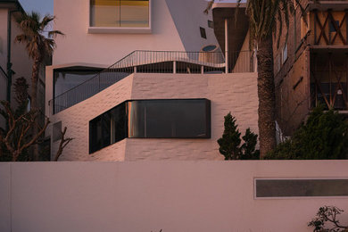 Modern three-storey concrete white house exterior in Sydney with a flat roof.