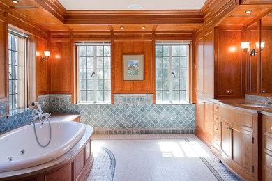 This is an example of a mid-sized traditional master bathroom in Bridgeport with raised-panel cabinets, medium wood cabinets, a drop-in tub, blue tile, travertine, brown walls, ceramic floors, an undermount sink, engineered quartz benchtops and white floor.