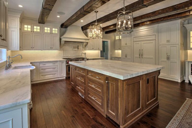 Inspiration for a large timeless medium tone wood floor, brown floor and exposed beam kitchen remodel in New York with a farmhouse sink, shaker cabinets, white cabinets, marble countertops, white backsplash, ceramic backsplash, stainless steel appliances, an island and gray countertops