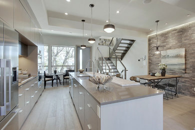 This is an example of a contemporary eat-in kitchen in Calgary with a single-bowl sink, flat-panel cabinets, grey cabinets, quartzite benchtops, white splashback, ceramic splashback, stainless steel appliances, medium hardwood floors and with island.