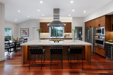 Eat-in kitchen - large craftsman l-shaped medium tone wood floor and red floor eat-in kitchen idea in San Francisco with an undermount sink, flat-panel cabinets, medium tone wood cabinets, quartzite countertops, white backsplash, marble backsplash, stainless steel appliances, an island and white countertops