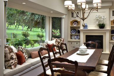 Example of a mid-sized classic medium tone wood floor enclosed dining room design in Other with beige walls and a standard fireplace