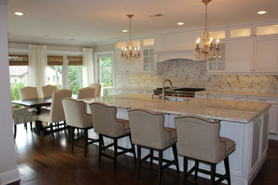 Example of a classic dark wood floor eat-in kitchen design in New York with an undermount sink, raised-panel cabinets, white cabinets, marble countertops, stone tile backsplash, stainless steel appliances and an island