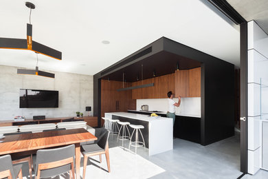 Design ideas for a mid-sized contemporary l-shaped eat-in kitchen in Sydney with an integrated sink, medium wood cabinets, quartz benchtops, white splashback, black appliances, concrete floors and with island.