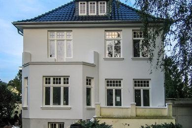 Photo of a large traditional two-storey white exterior in Hamburg with stone veneer.