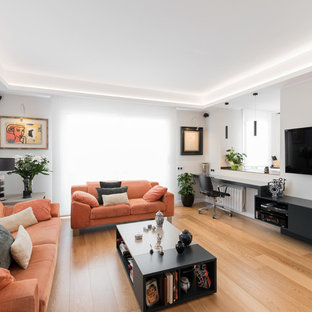 Ejemplo de sala de estar actual con paredes blancas, suelo de madera clara y televisor colgado en la pared