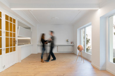 Imagen de sala de estar con rincón musical abierta tradicional renovada grande sin chimenea y televisor con paredes blancas, suelo laminado y suelo marrón
