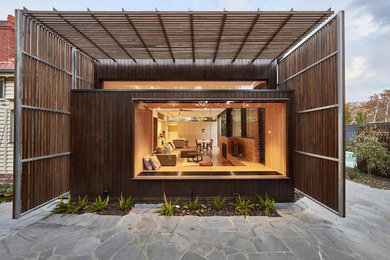 This is an example of a mid-sized contemporary one-storey brown house exterior in Melbourne with wood siding, a flat roof and a metal roof.