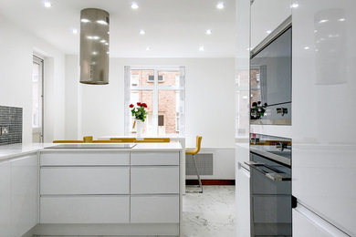 Design ideas for a large modern grey and cream u-shaped kitchen/diner in London with a built-in sink, flat-panel cabinets, white cabinets, grey splashback, glass sheet splashback, stainless steel appliances, marble flooring and a breakfast bar.