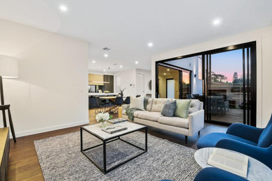 This is an example of a mid-sized modern living room in Melbourne with white walls and medium hardwood floors.