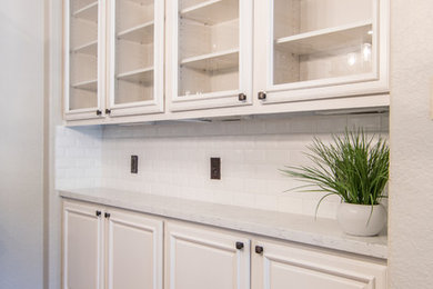 This is an example of a large traditional u-shaped eat-in kitchen in Houston with a farmhouse sink, raised-panel cabinets, white cabinets, quartzite benchtops, white splashback, subway tile splashback, stainless steel appliances, ceramic floors and with island.