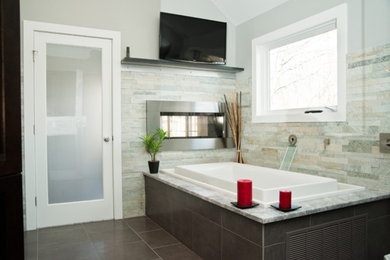 Large contemporary master bathroom in New York with a drop-in tub, gray tile, stone tile, grey walls and porcelain floors.