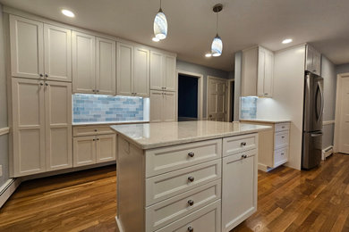 Inspiration for a large modern medium tone wood floor eat-in kitchen remodel in Boston with an undermount sink, shaker cabinets, white cabinets, quartz countertops, blue backsplash, porcelain backsplash, stainless steel appliances, an island and white countertops