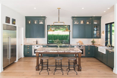 Photo of a large country galley eat-in kitchen in San Francisco with a drop-in sink, flat-panel cabinets, green cabinets, marble benchtops, white splashback, ceramic splashback, stainless steel appliances, medium hardwood floors, with island, brown floor and white benchtop.