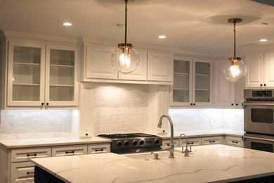 Example of a l-shaped dark wood floor kitchen pantry design in Dallas with a farmhouse sink, raised-panel cabinets, white cabinets, quartz countertops, white backsplash, mosaic tile backsplash, stainless steel appliances and an island