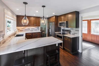 Example of a mid-sized transitional u-shaped dark wood floor and brown floor enclosed kitchen design in Portland with an undermount sink, shaker cabinets, dark wood cabinets, quartzite countertops, multicolored backsplash, ceramic backsplash, stainless steel appliances, a peninsula and multicolored countertops