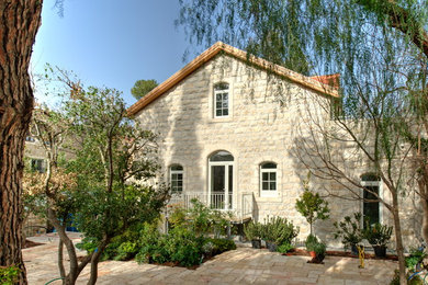 This is an example of a mid-sized modern three-storey beige exterior in Other with stone veneer, a gable roof and a tile roof.