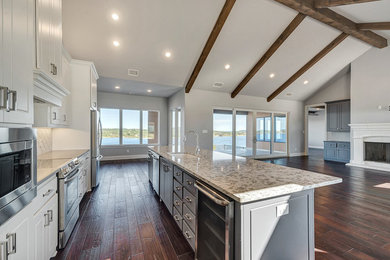 Open concept kitchen - large contemporary single-wall medium tone wood floor and brown floor open concept kitchen idea in Dallas with an undermount sink, stainless steel appliances, raised-panel cabinets, white cabinets, granite countertops, white backsplash, ceramic backsplash and an island