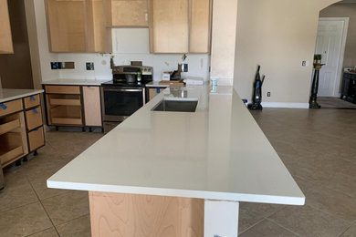 Example of a mid-sized minimalist l-shaped kitchen design in Miami with an undermount sink, stainless steel appliances and white countertops