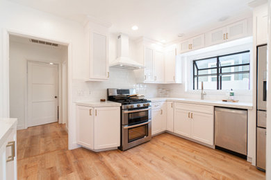 Example of a vinyl floor kitchen design in Los Angeles with an undermount sink, white cabinets, quartzite countertops, white backsplash and white countertops