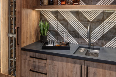 Example of a mid-sized transitional single-wall concrete floor and white floor wet bar design in Other with an undermount sink, flat-panel cabinets, light wood cabinets, concrete countertops, black backsplash, porcelain backsplash and black countertops