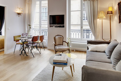 Inspiration pour un petit salon bohème ouvert avec un mur gris, parquet clair, aucune cheminée, un téléviseur encastré et un sol marron.