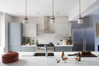 Inspiration for a large modern galley open plan kitchen in London with an integrated sink, grey cabinets, solid surface benchtops, grey splashback, subway tile splashback, stainless steel appliances, limestone floors and with island.