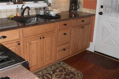 Example of a classic medium tone wood floor kitchen pantry design in New York with a drop-in sink, raised-panel cabinets, light wood cabinets, beige backsplash and stainless steel appliances