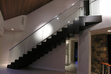 Large trendy wooden floating glass railing staircase photo in Philadelphia with wooden risers