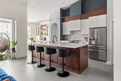 Inspiration for a mid-sized modern galley porcelain tile and gray floor kitchen remodel in Orlando with an undermount sink, white cabinets, quartz countertops, white backsplash, ceramic backsplash, stainless steel appliances, an island and white countertops