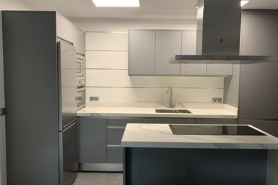 Ejemplo de cocina minimalista pequeña con fregadero de doble seno, armarios con paneles lisos, puertas de armario grises, encimera de cuarzo compacto, salpicadero blanco, salpicadero de azulejos de cerámica, electrodomésticos de acero inoxidable, suelo de baldosas de cerámica, una isla, suelo gris y encimeras blancas