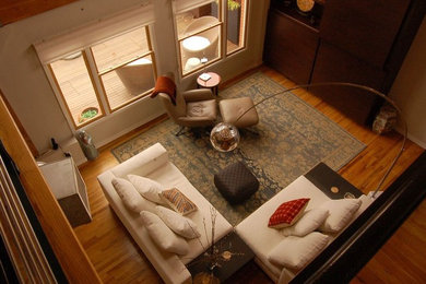 Example of a mid-sized trendy enclosed medium tone wood floor living room design in Denver with white walls and no fireplace