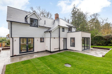 This is an example of a large and gey traditional two floor rear detached house in London with mixed cladding, a lean-to roof and a tiled roof.