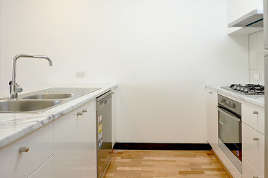 Photo of a traditional kitchen in Melbourne with a double-bowl sink, marble benchtops, white splashback, porcelain splashback and medium hardwood floors.