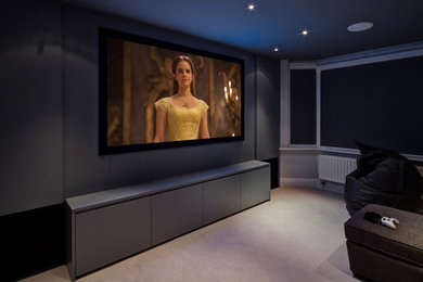 Foto de cine en casa cerrado contemporáneo de tamaño medio con paredes grises, moqueta, pantalla de proyección y suelo beige