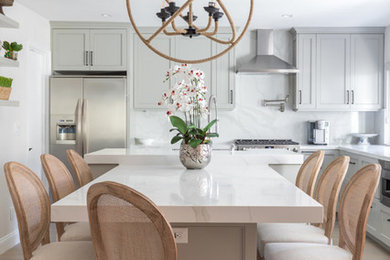 Example of a mid-sized trendy l-shaped light wood floor and brown floor eat-in kitchen design in Orange County with shaker cabinets, gray cabinets, quartz countertops, white backsplash, stainless steel appliances, two islands and white countertops