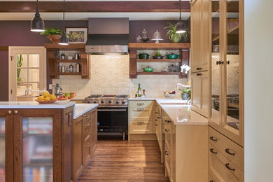 Photo of a large traditional l-shaped eat-in kitchen in Portland with a farmhouse sink, recessed-panel cabinets, dark wood cabinets, quartzite benchtops, white splashback, porcelain splashback, stainless steel appliances, medium hardwood floors, with island and white benchtop.