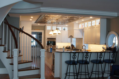 Open concept kitchen - traditional u-shaped dark wood floor open concept kitchen idea in Cleveland with a farmhouse sink, recessed-panel cabinets, white cabinets, granite countertops, white backsplash, porcelain backsplash, stainless steel appliances and an island